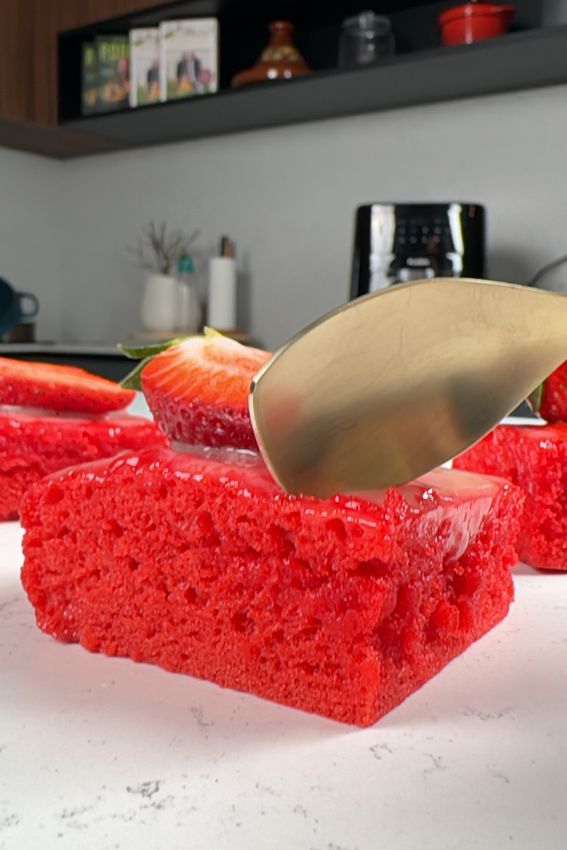 colher dourada a partir brownies vermelhos aos quadradinhos com cobertura de chocolate branco e morangos